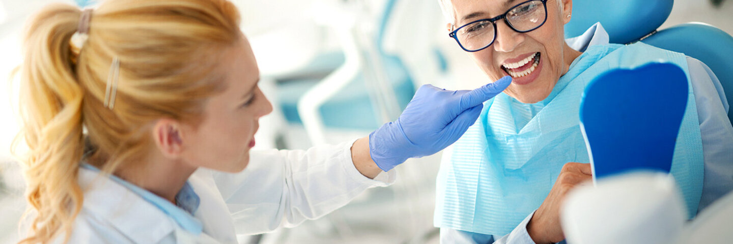 Eine Zahnärztin erklärt einer Patientin, an welchen Stellen der Zahnersatz gereinigt werden muss.
