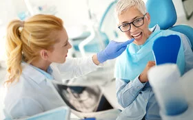 Eine Zahnärztin erklärt einer Patientin, an welchen Stellen der Zahnersatz gereinigt werden muss.