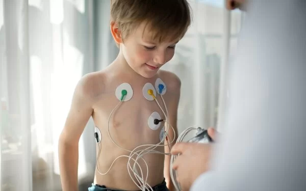 Ein Arzt stellt einen EKG-Holter-Monitor für ein Kind ein, um seine Herzgesundheit zu überprüfen.
