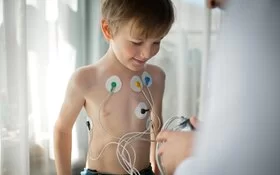 Ein Arzt stellt einen EKG-Holter-Monitor für ein Kind ein, um seine Herzgesundheit zu überprüfen.