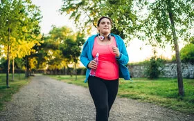 Eine Frau mit PCOS joggt durch einen Park.