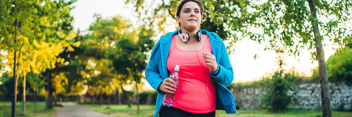 Eine Frau mit PCOS joggt durch einen Park.