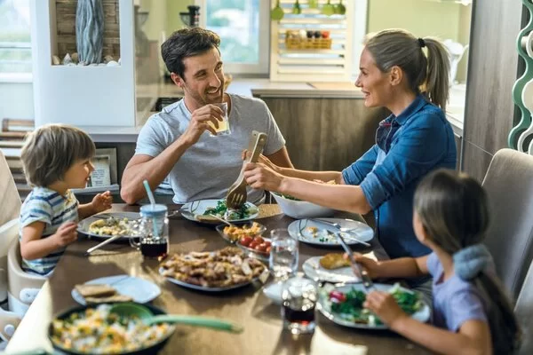 Eine Familie (Vater, Mutter und 2 kleine Kinder) sitzen am Frühstückstisch.