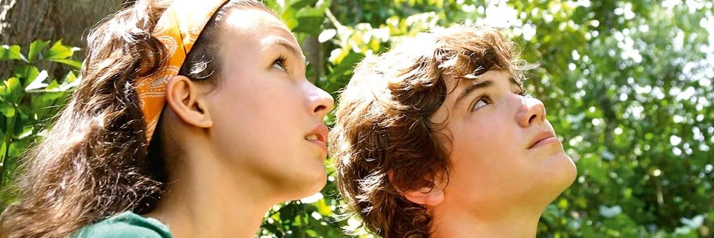Zwei Kinder schauen während ihres Outdoor-Unterrichts in die Baumkronen.