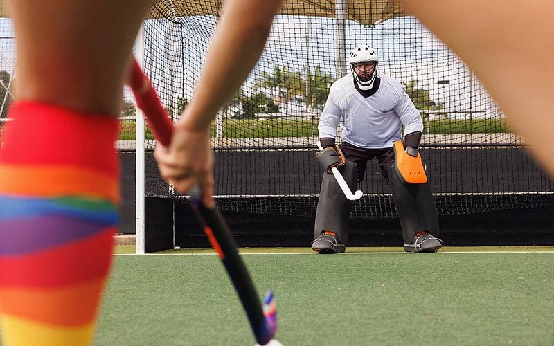 Eine Person zielt mit einem Schläger auf ein Hockeytor.
