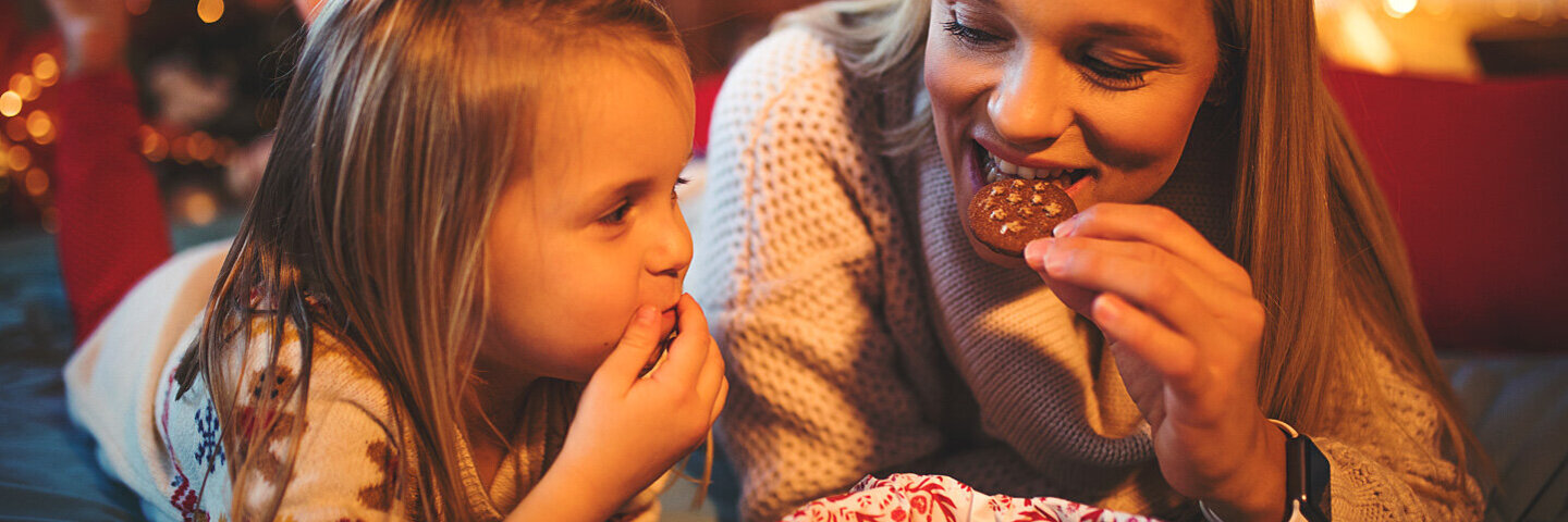 Mutter und Tochter essen achtsam Kekse.