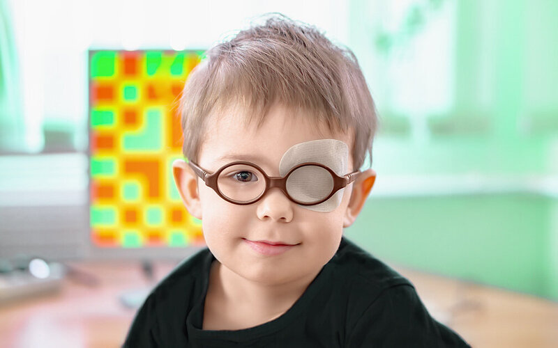 Einem kleinen Jungen mit Brille wurde ein Pflaster über das linke Auge geklebt, um sein Schielen zu korrigieren.