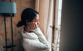 Frau mit Klimaangst schaut besorgt aus dem Fenster.