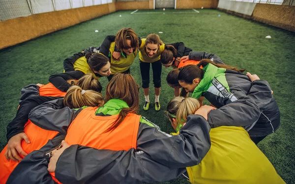 Frauen einer Fußballmannschaft stecken die Köpfe zusammen.