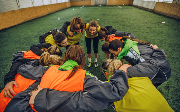 Frauen einer Fußballmannschaft stecken die Köpfe zusammen.