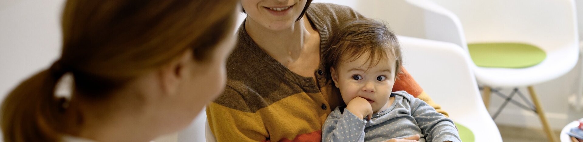 Mutter hält Baby auf dem Arm und bei schauen zu einer Kinderärztin.