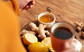 Frau macht sich einen Tee mit Ingwer und Honig, um die Gesundheit zu fördern.