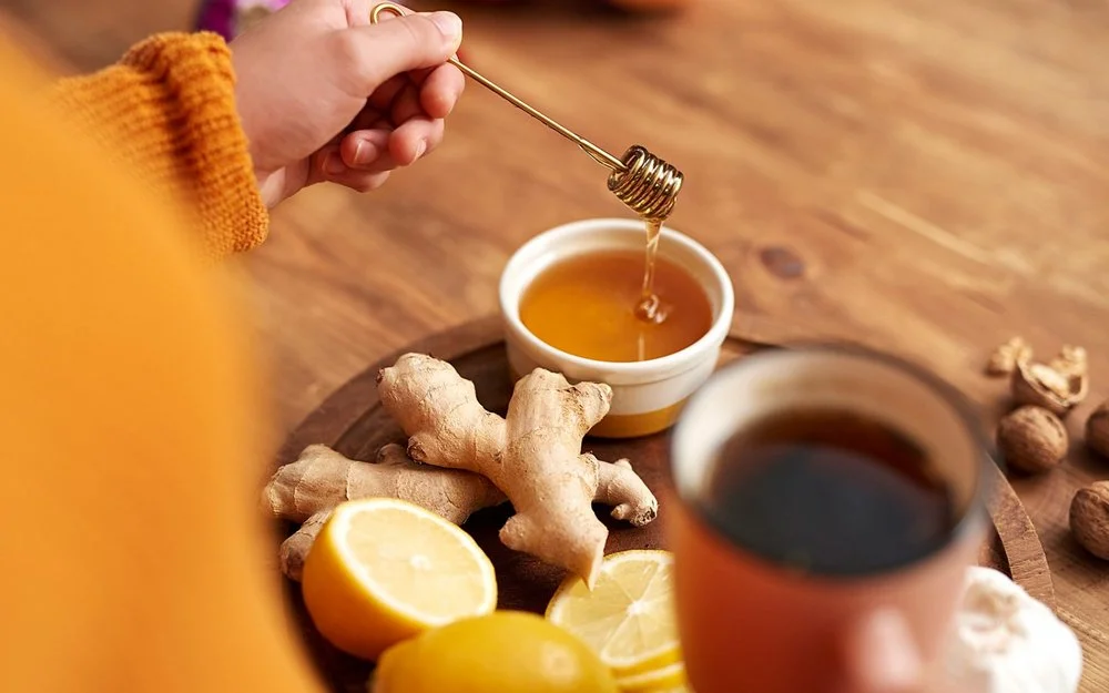 Frau macht sich einen Tee mit Ingwer und Honig, um die Gesundheit zu fördern.