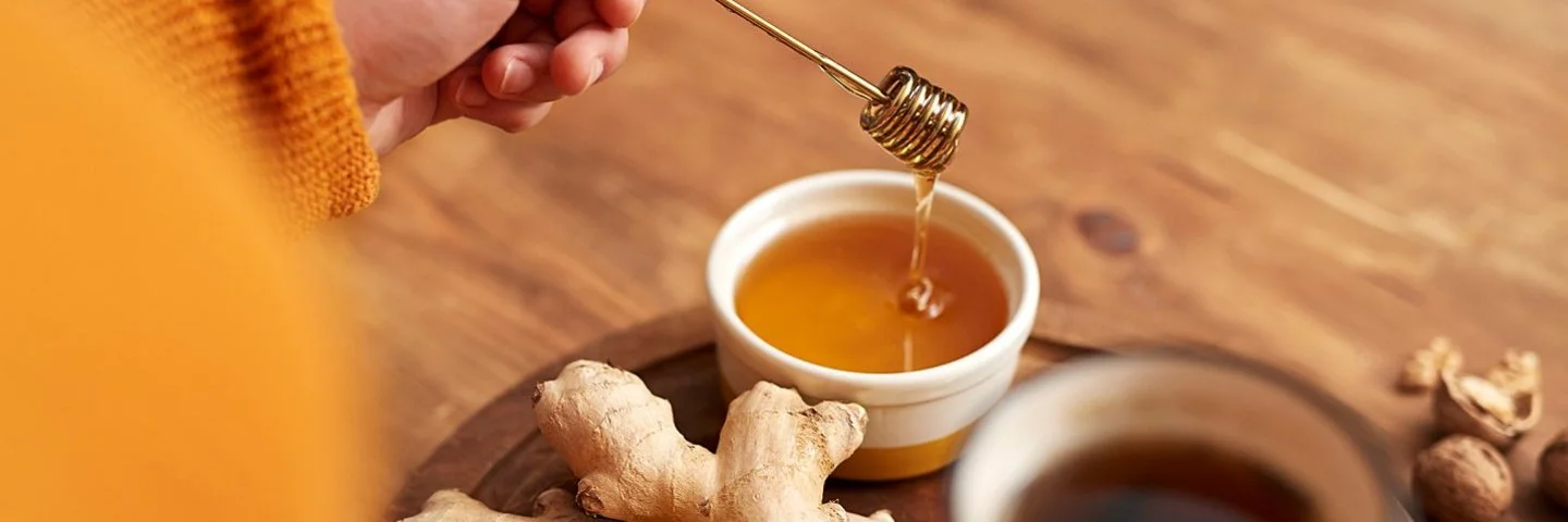 Frau macht sich einen Tee mit Ingwer und Honig, um die Gesundheit zu fördern.