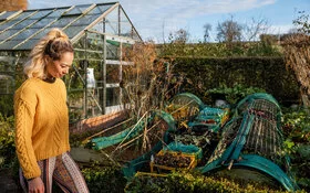 Frau geht durch ihren Schrebergarten, der nach dem Prinzip der Permakultur angelegt wurde.