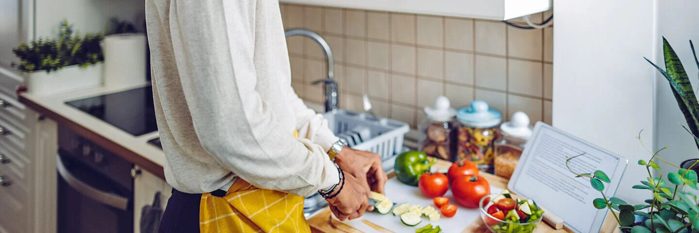 Ein junger Mann kocht für sich selbst ein gesundes Essen.