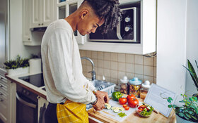 Ein junger Mann kocht für sich selbst ein gesundes Essen.
