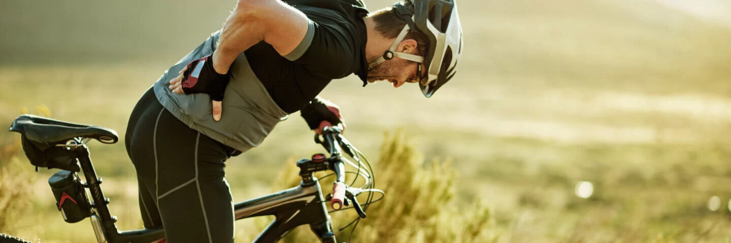 Ein Radfahrer fasst sich wegen seines Seitenstechens schmerzerfüllt in die Seite.