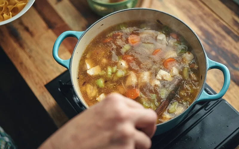 Eine Hühnersuppe gilt als Omas Hausmittel gegen eine Erkältung. Hier mit frischem Gemüse in einem Topf.