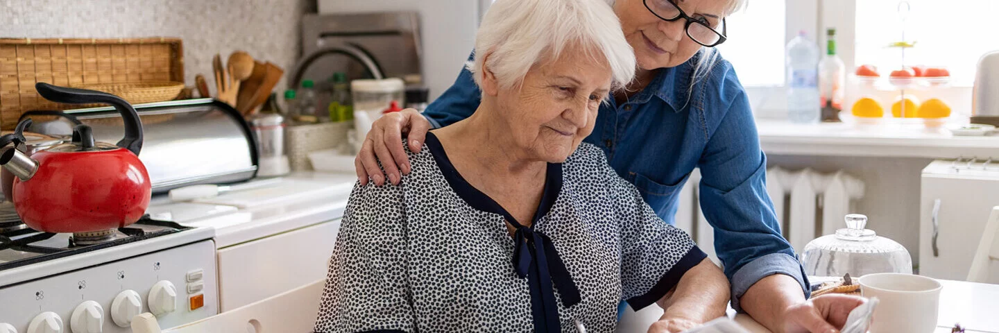 Eine ältere Frau hilft ihrer Mutter bei dem Sichten von Unterlagen bezüglich Vollmachten und Patientenverfügungen.