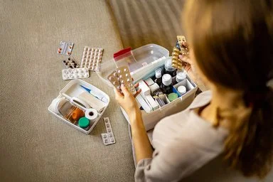 Eine Frau sortiert Ihre Medikamente in Ihrer Hausapotheke.