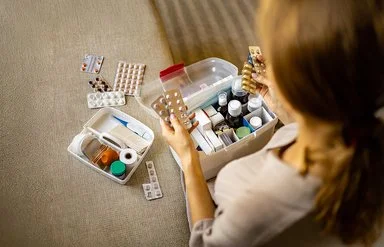 Eine Frau sortiert Ihre Medikamente in Ihrer Hausapotheke.