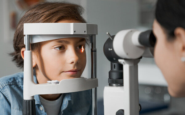 Ein Junge mit Sehschwäche ist beim Augenarzt, wo seine Augen und Sehstärke vermessen werden.