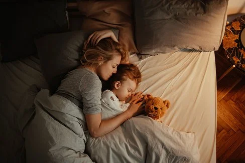 Draufsicht auf eine schlafende Frau und ein schlafendes Kind in einem Bett.