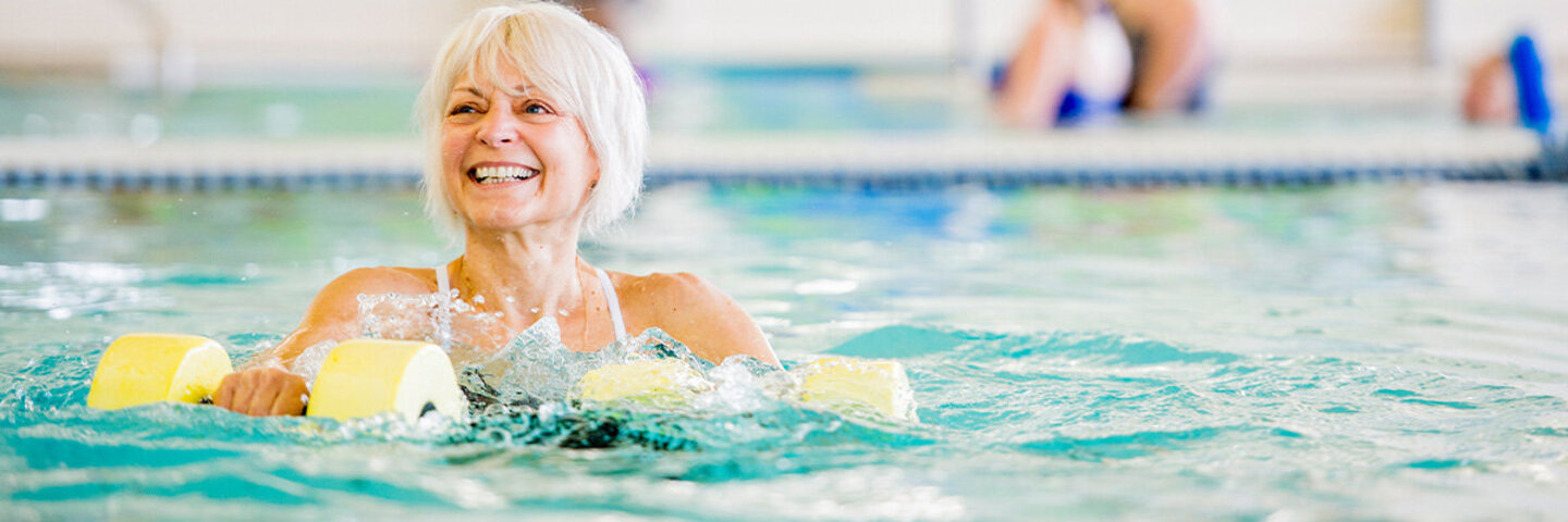 Frau trainiert mit Geräten im Wasser, damit das Schwimmen noch effektiver wird.