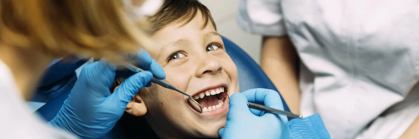 Ein Junge wird bei der zahnärztlichen Vorsorgeuntersuchung von einer Kinderzahnärztin behandelt.