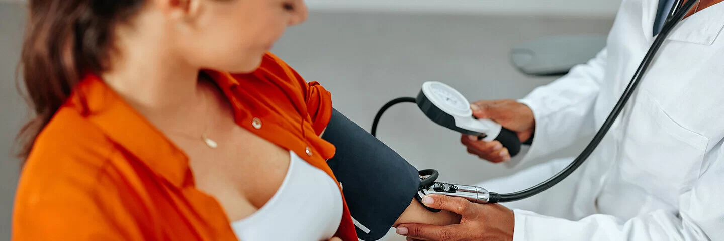 Schwangere Frau lässt ihren Blutdruck von einer medizinischen Fachkraft checken.
