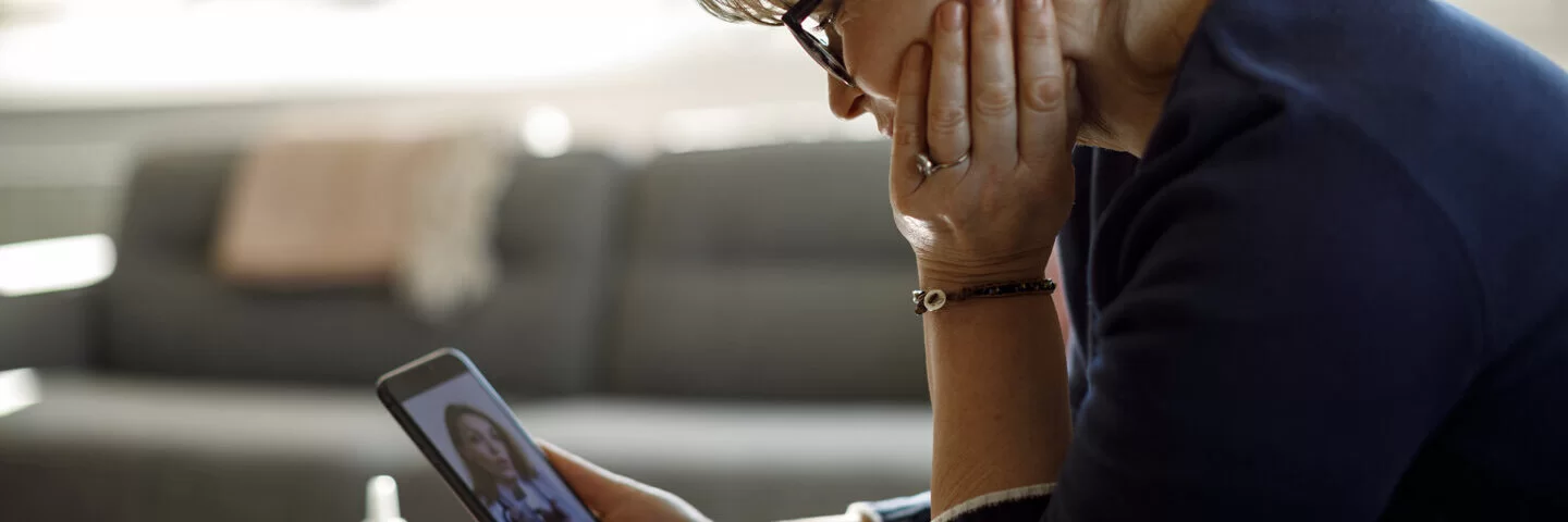 Eine an Angststörungen leidende Frau schaut auf ihr Smartphone.