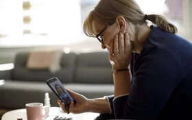 Eine an Angststörungen leidende Frau schaut auf ihr Smartphone.