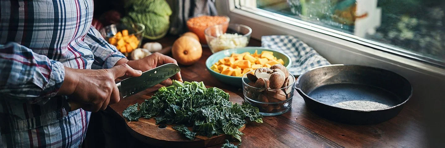 Eine Frau schneidet Grünkohl auf einem Schneidebrett in der Küche.