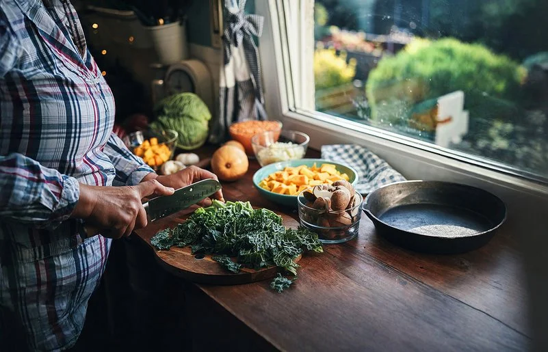 Eine Frau schneidet Grünkohl auf einem Schneidebrett in der Küche.