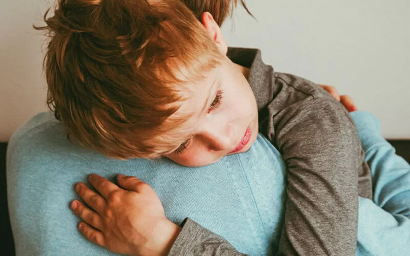 Ein Kind ist auf dem Arm genommen und traurig – jemand in der Familie ist schwerkrank. Wie man mit dem Tod umgeht.