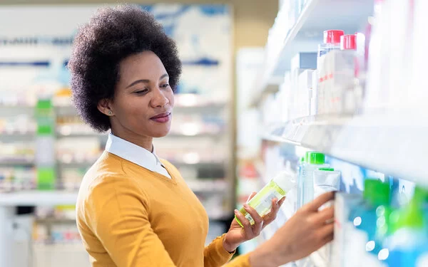 Frau steht in der Drogerie und sucht sich Kosmetikprodukte aus.