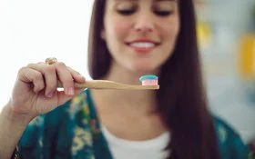 Frau legt Wert auf nachhaltige Zahnpflege und greift zur Bambus-Zahnbürste.