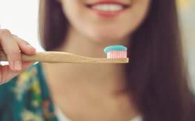 Frau legt Wert auf nachhaltige Zahnpflege und greift zur Bambus-Zahnbürste.