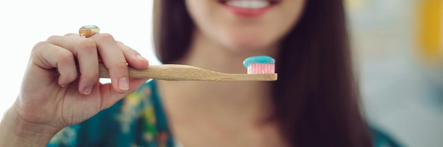 Frau legt Wert auf nachhaltige Zahnpflege und greift zur Bambus-Zahnbürste.