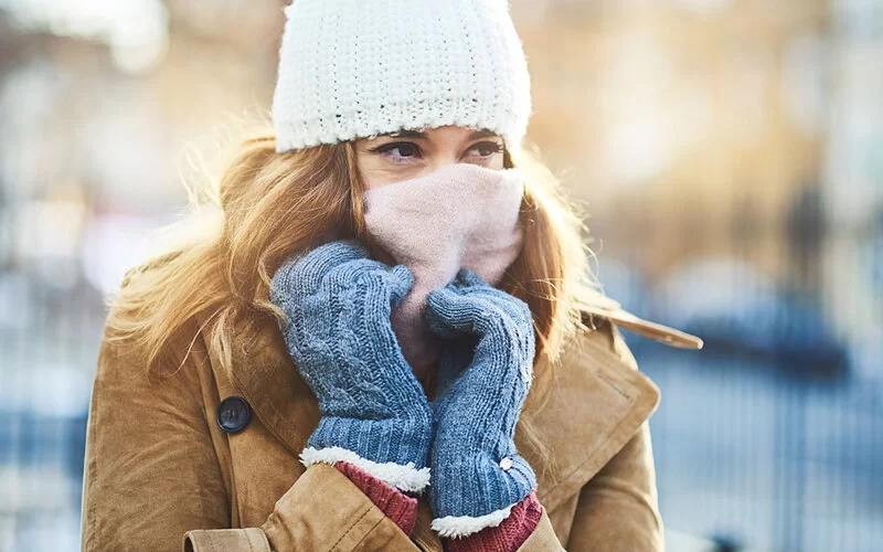 Frau mit Raynaud-Syndrom ist für einen winterlichen Ausflug dick eingepackt, vor allem Handschuhe dürfen nicht fehlen.