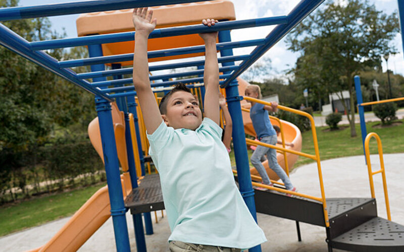 Ein Junge spielt auf dem Spielplatz an einem Klettergerüst.