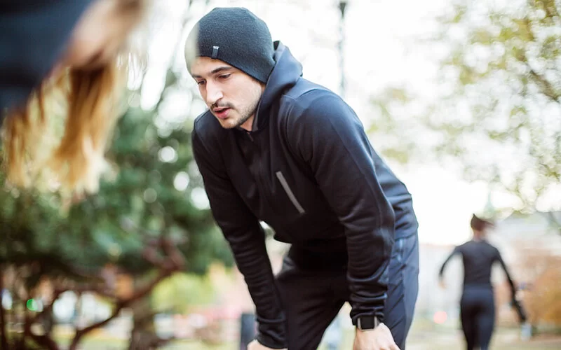 Ein junger Mann ist vom Joggen erschöpft und macht eine Pause.