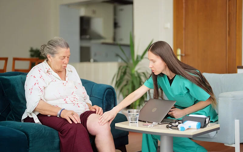 Eine Ärztin untersucht das Bein einer Patientin, um eine Beinvenenthrombose ausschließen zu können.