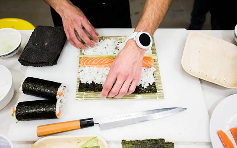 Mann bereitet sich Sushi mit rohem Fisch zu und setzt somit auf Rohkost.