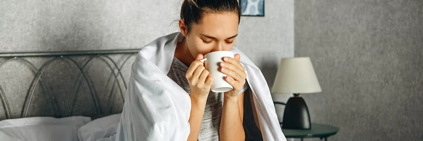 Frau trinkt Wintertee im Bett.