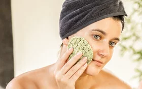 Eine Frau wäscht sich mit einem nachhaltigen Schwamm das Gesicht.