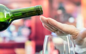 Frau macht Alkoholverzicht und schlägt einen Rotwein aus.