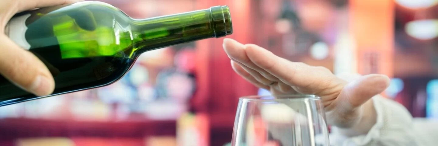 Frau macht Alkoholverzicht und schlägt einen Rotwein aus.