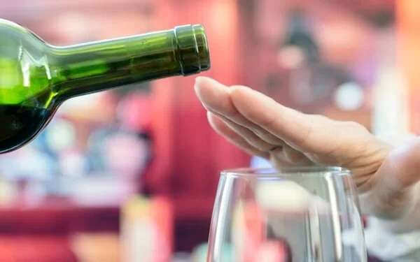 Frau macht Alkoholverzicht und schlägt einen Rotwein aus.
